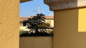Vista a través de un arco de piedra que da a un edificio con techo de tejas y un árbol.