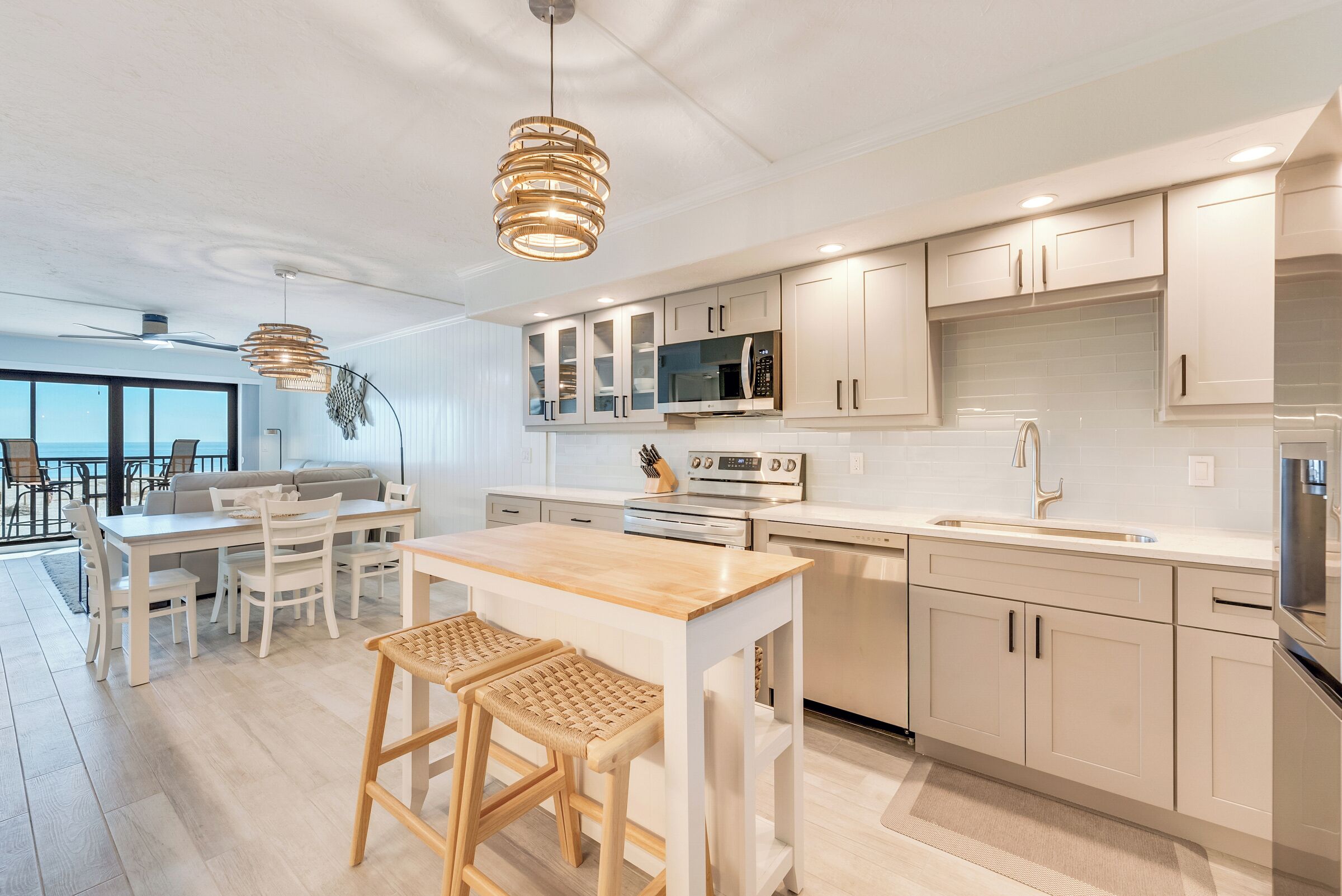 A modern kitchen with white cabinetry, a wooden island, and pendant lighting.