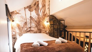 Een slaapkamer met een bed, een houten vloer, een trap en een muurschildering.