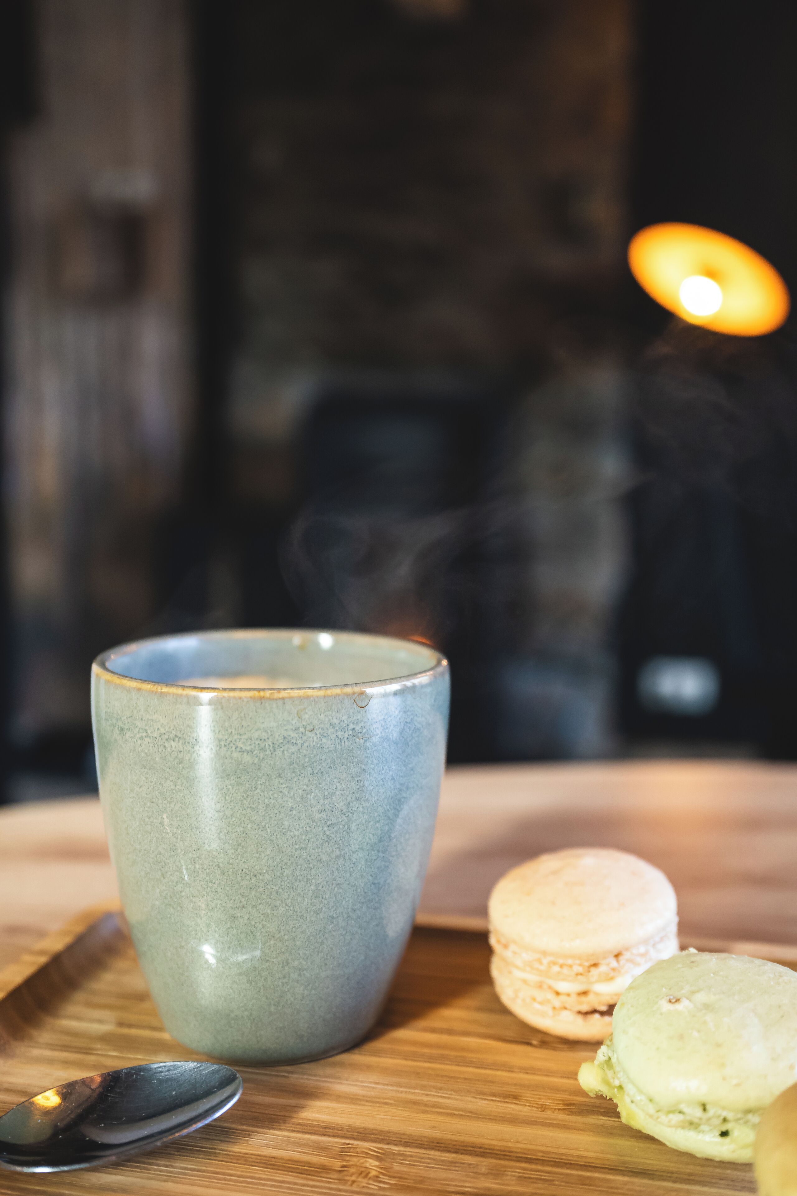 En keramikmølje, en ske og to macarons på en træoverflade.