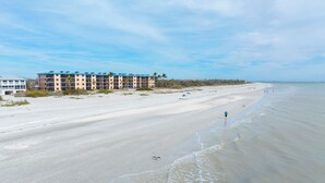 A beach with a row of multi-story buildings in the background. - OCEAN'S REACH 2X2: 1-Bdrm, Gulf-Front View, All Amenities Open! (Sanibel Island)