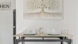 A dining area with a table and two benches, a painting of a tree on the wall, and a sign with the word "WHEN". - Detached Private Guesthouse - Full Kitchen, 1BD + 1BA, Parking Spot - Sleeps 2 (Mesa)
