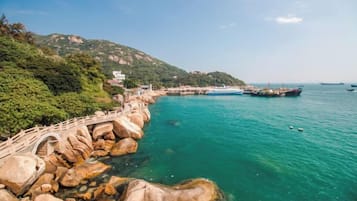 A coastal area with a rocky shoreline, a bridge, and boats in the water.