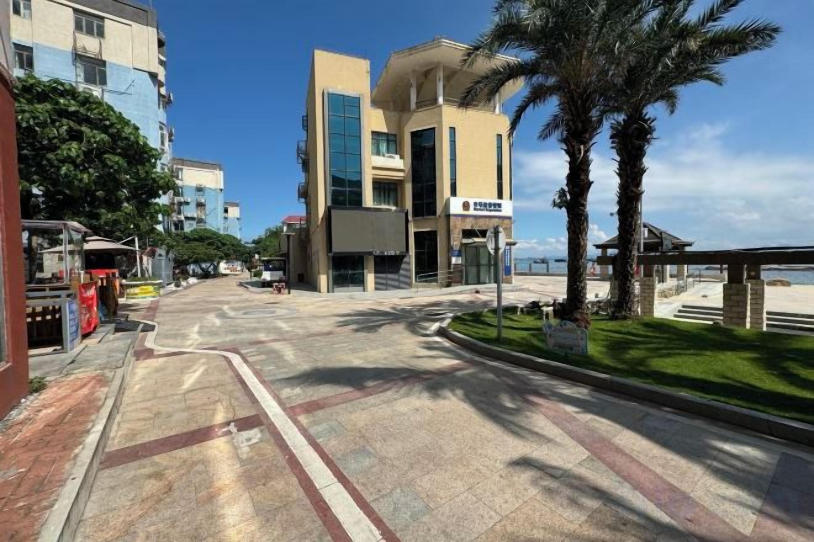 A street with buildings, a clear sky, and a palm tree.