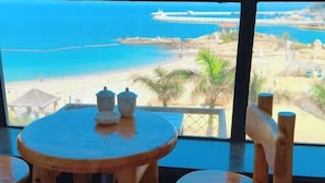 A wooden table and chair set with a view of a beach and rocky coastline. - Zhuhai Wailingding Island Wanghaige (Beach Swimming Area) (Zhuhai)