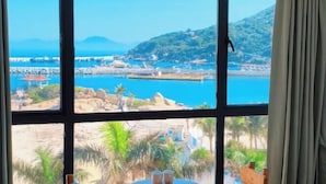 A room with a large window overlooking a coastal area, a table with two cups, and a view of a pier and mountains. - Zhuhai Wailingding Island Wanghaige (Beach Swimming Area) (Zhuhai)