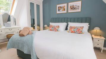 A bedroom with a large bed, two side tables, a dresser, and a window.