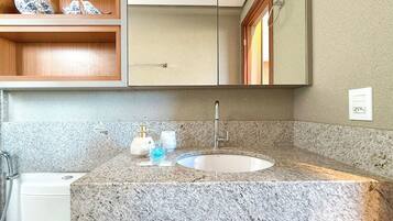 A bathroom with a granite countertop, a sink, a mirror, and wooden cabinets.