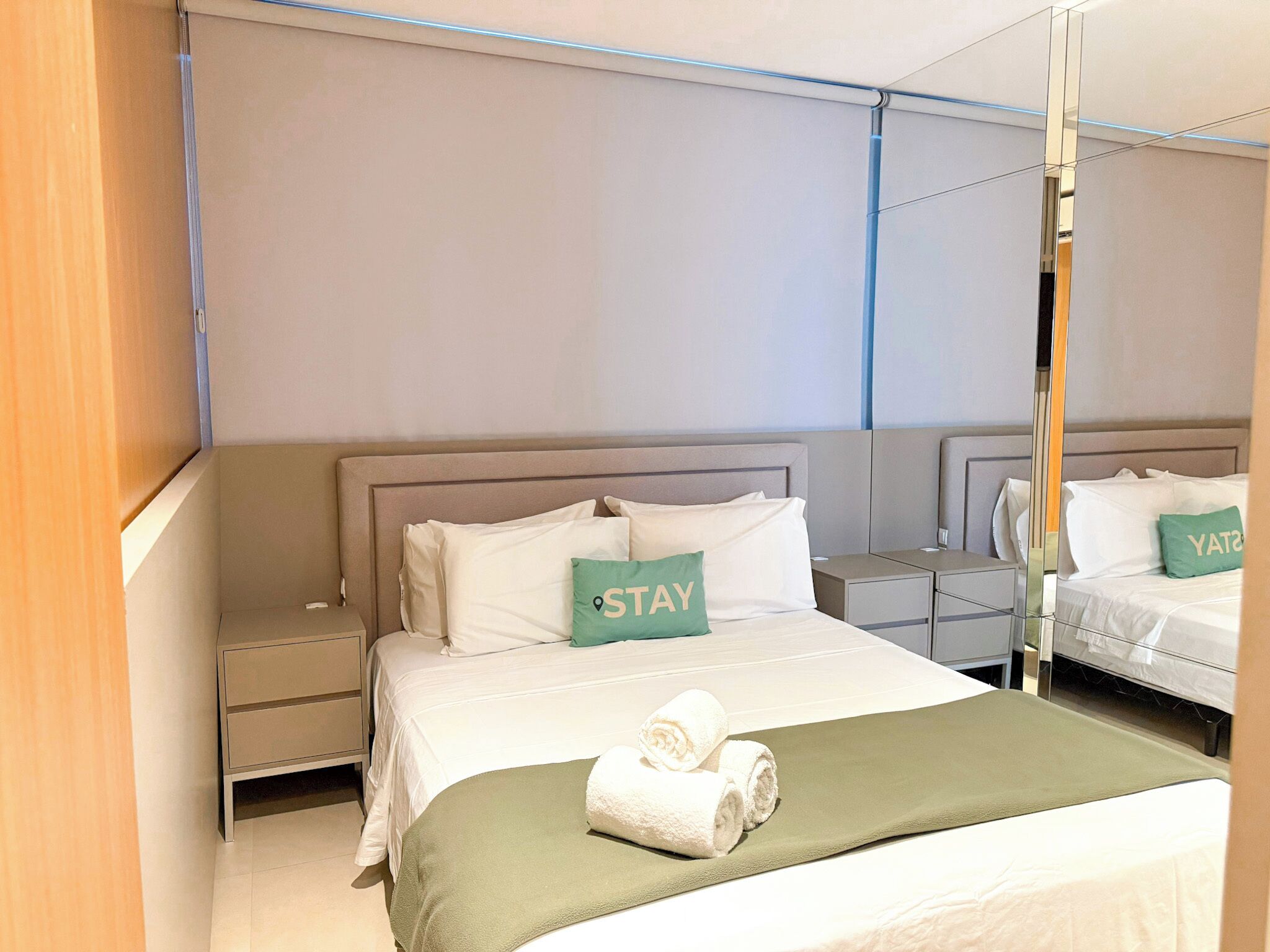 Una habitación de hotel con una cama grande, una mesita de noche y un armario.