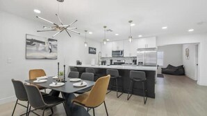 A modern kitchen with white cabinets, a central island, and a dining area with a table and chairs. - Perfect for Large Group  5BD+3BA Free Parking (Mesa)