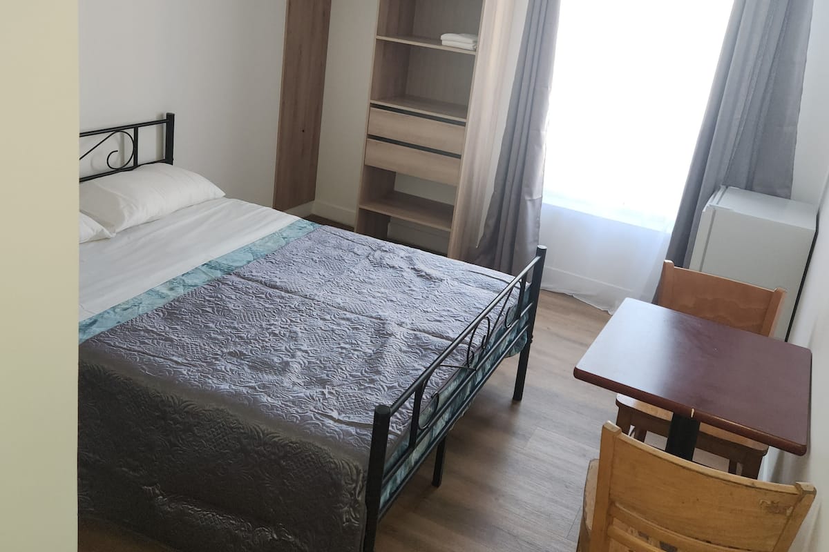 Une chambre à coucher avec un lit, une armoire en bois, une table et une chaise.