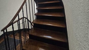 Una escalera de madera con barandilla que conduce a una puerta con ventanal.