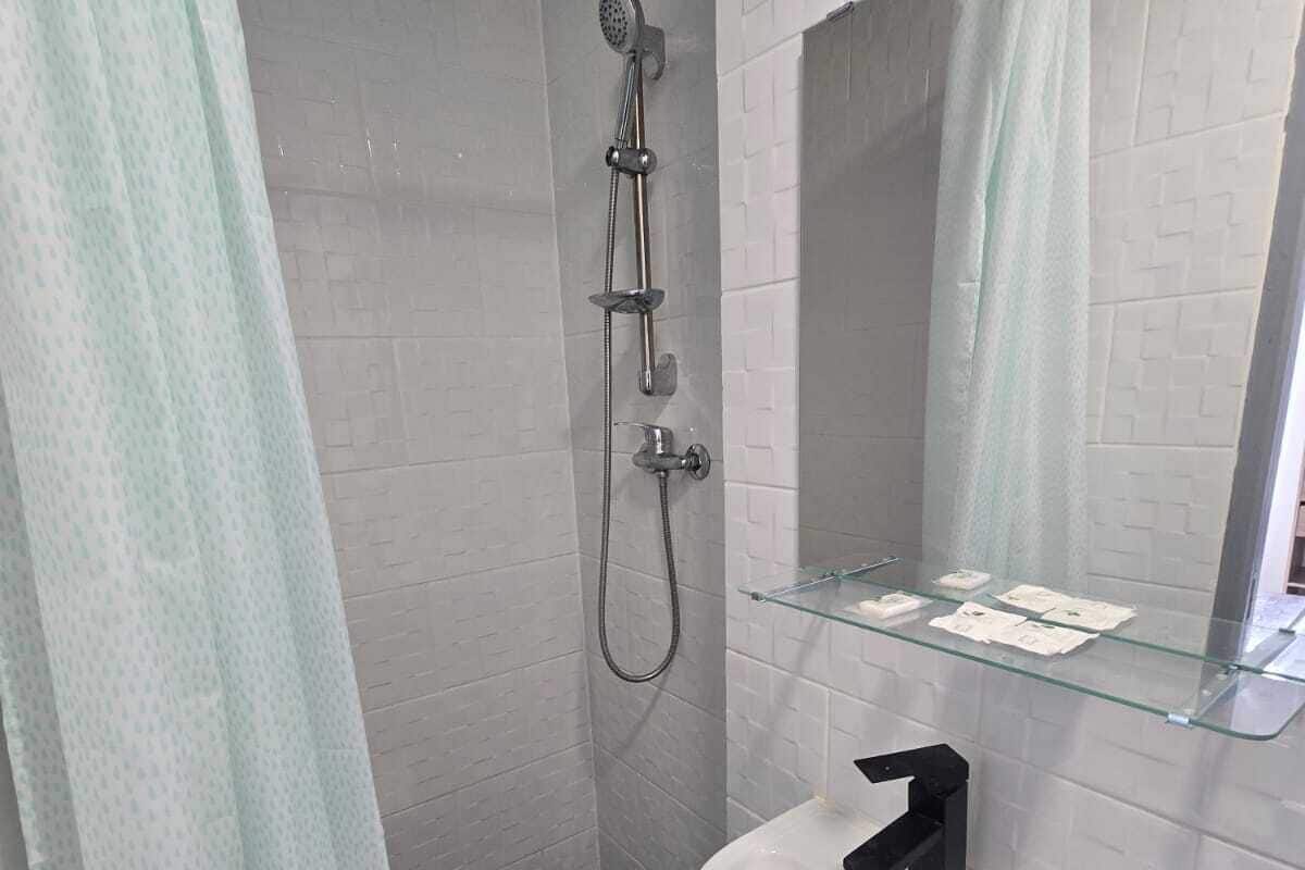 Une salle de bain avec une douche, un lavabo et une étagère en verre.