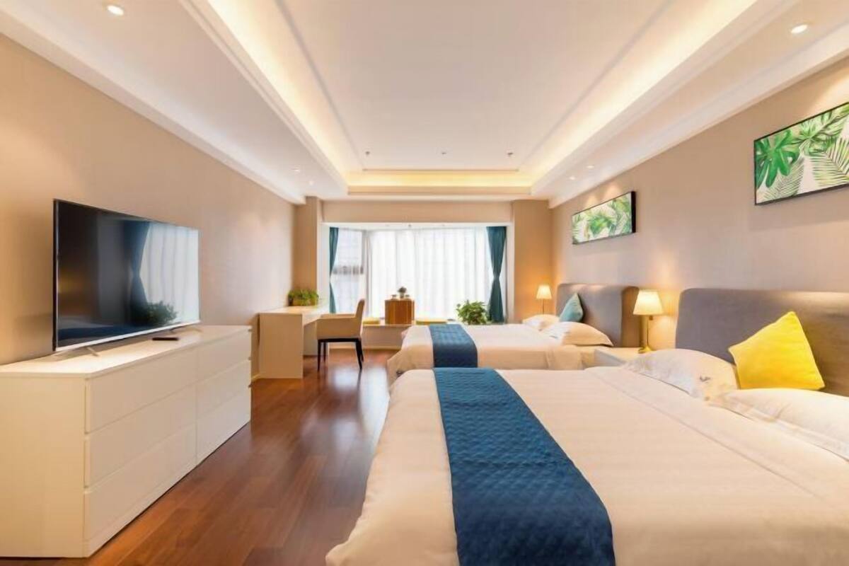 Ein Hotelzimmer mit zwei Betten, einem Fernseher, einem Schreibtisch und einem Sessel.