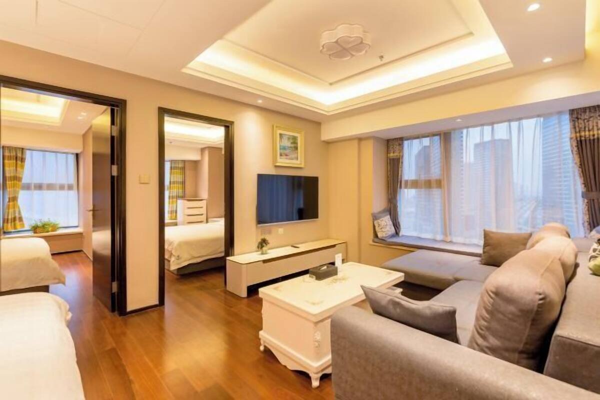 Ein modernes Hotelzimmer mit Sofa, Fernseher, Nachttisch und großem Fenster.