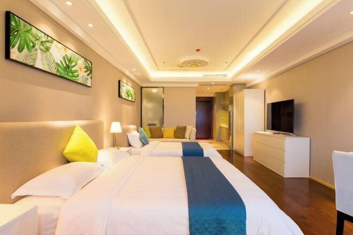 Ein Hotelzimmer mit zwei Betten, einem Fernseher, einem Schminktisch und einem Bild an der Wand.