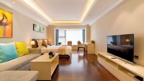 A modern hotel room with a sofa, a bed, a desk, and a TV. - Zhanyou Home Sea View Apartment Hotel(Dalian Venice the City of Water) (Dalian)