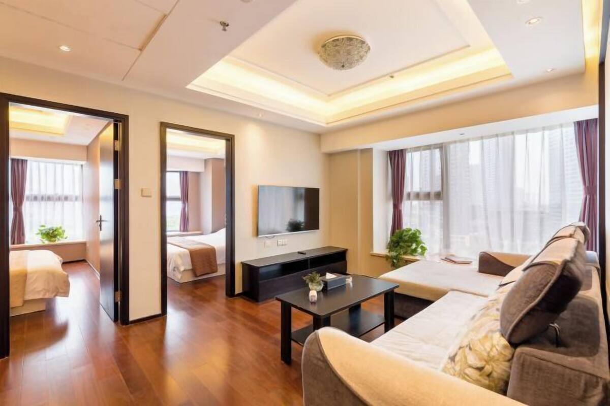 Ein modernes Hotelzimmer mit einer Couch, einem Fernseher, einem kleinen Tisch und einem Bett.