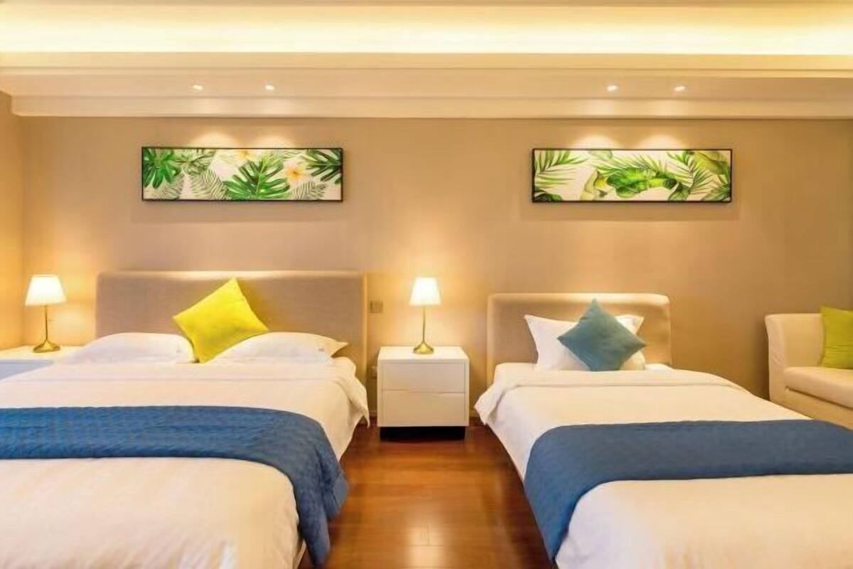 Ein Hotelzimmer mit zwei Betten, jeweils einem Nachttisch und einer Lampe, und einem großen Gemälde an der Wand.