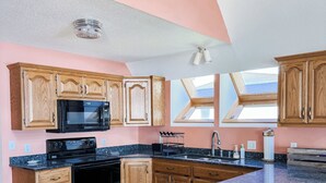 Una cocina con armarios de madera, estufa negra y encimera de granito.