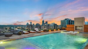 A rooftop pool with lounge chairs and a city skyline view at dusk. - Sleeps 34! 11 Condos in New Austin High Rise w/ Rooftop Pool, Gym, Yoga Studio (Austin)