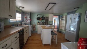Una cocina con armarios de madera, un lavamanos, una encimera, un refrigerador y una estufa.