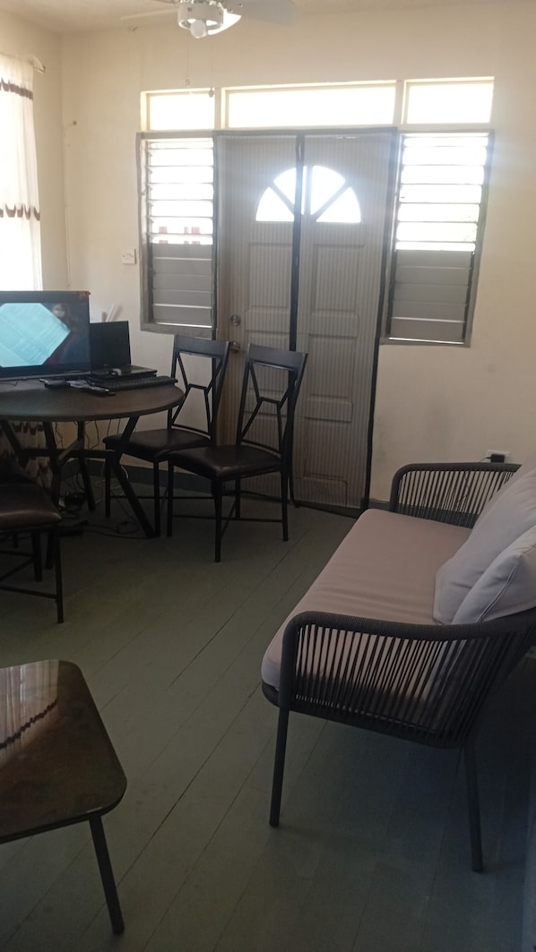 A room with a bed, two chairs, a desk with a laptop, and a window with blinds.