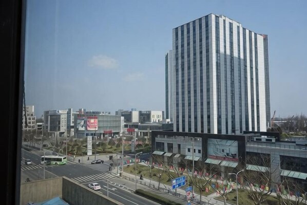 A modern building with a vertical design, a road with vehicles, and a clear sky. - Pod Inn Hotel (Shanghai Wusong International Cruise) (Shanghai)
