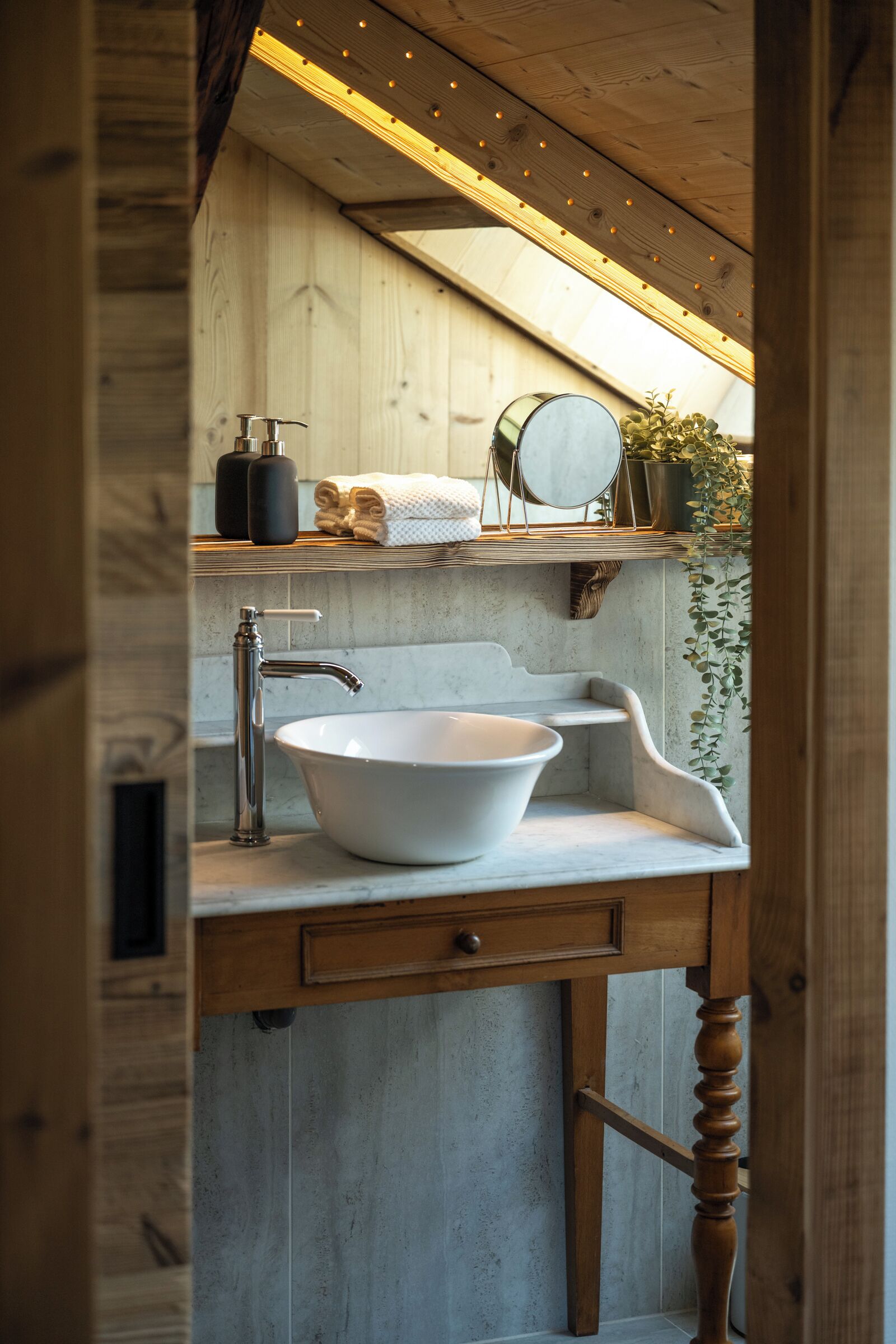 A bathroom with a wooden vanity, a white sink, and a mirror.