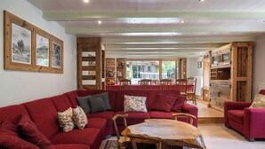 A cozy living room with a red sofa, wooden chairs, and a central table.