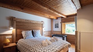 A wooden-framed bedroom with a bed, nightstands, a window, and a radiator.