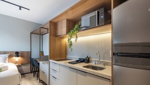 Una cocina moderna con microondas, fregadero y refrigerador. Hay una planta colgando sobre la encimera y una pequeña mesa con sillas.
