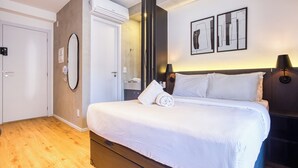 Habitación de hotel moderna con una cama grande, un armario, un espejo y dos lámparas fijadas a la pared.