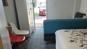 A hotel room with a bed, a desk, a chair, and a view of the street outside. - 1 Double and 1 sofa bed Studio (Auckland)