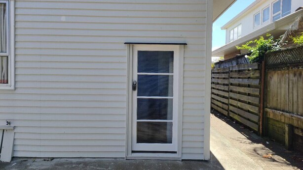 A white house with a front door and a small window. - 1 Double and 1 sofa bed Studio (Auckland)