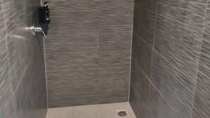 A modern bathroom with grey tiled walls, a shower area, and a sink. - 1 Double and 1 sofa bed Studio (Auckland)