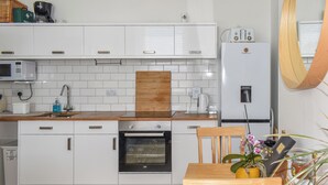 Een moderne keuken met witte kastjes, een houten aanrecht, een inbouwoven, een koffiezetapparaat en een koelkast.
