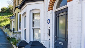 Een rij witte herenhuisjes met zwarte deuren en genummerde ramen.