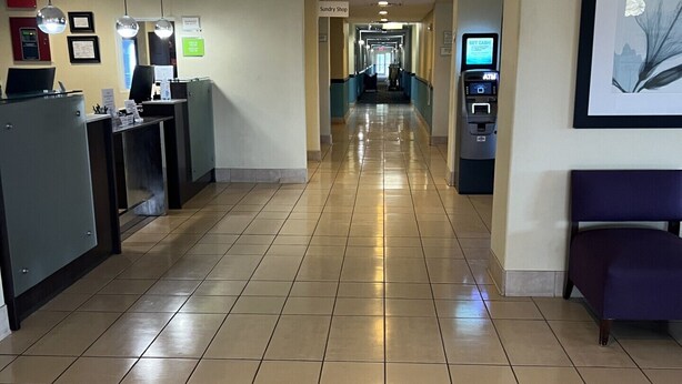 A hotel reception area with a reception desk, a Sundry Shop sign, and an ATM machine. - MATHIS DELUXE HOSPITALITY (Mathis)