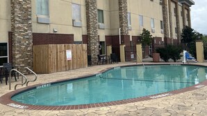 A hotel with a swimming pool, stone-tiled deck, and a brick wall with a wooden fence. - MATHIS DELUXE HOSPITALITY (Mathis)