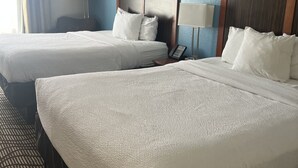 A hotel room with two beds, a desk, and a lamp. - MATHIS DELUXE HOSPITALITY (Mathis)