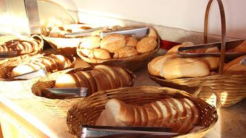 Un buffet proposant une variété de pains et de viennoiseries présentés dans des paniers en osier.