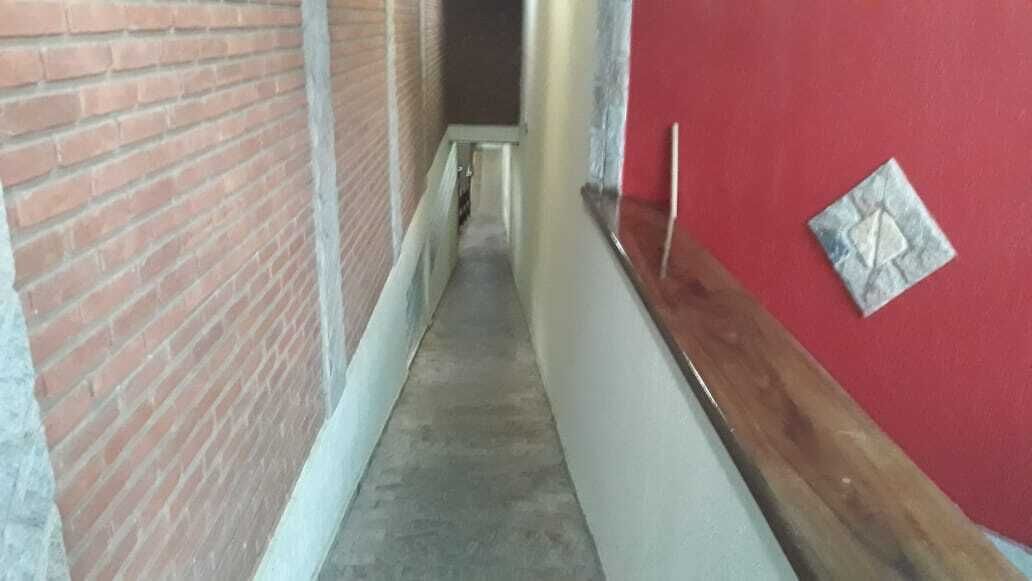 Un pasillo estrecho con paredes de ladrillo y una pared roja con un detalle decorativo.