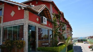 A building with a red facade, a reception area, and a parking lot. - Hotel do Papai Noel  (Itatiaia)