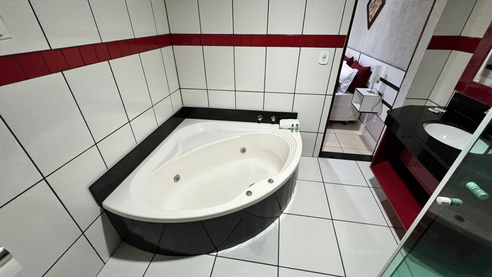 A modern bathroom with a freestanding bathtub, white tiled walls, and a red accent strip.