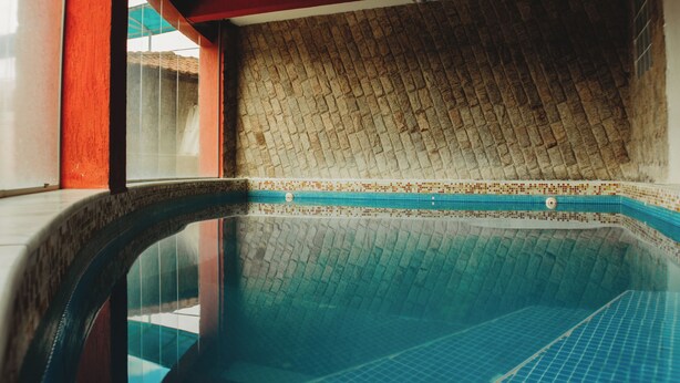 A swimming pool with a tiled wall and a red accent wall. - Hotel do Papai Noel  (Itatiaia)