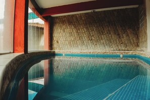 A swimming pool with a tiled wall and a red accent wall. - Hotel do Papai Noel  (Itatiaia)
