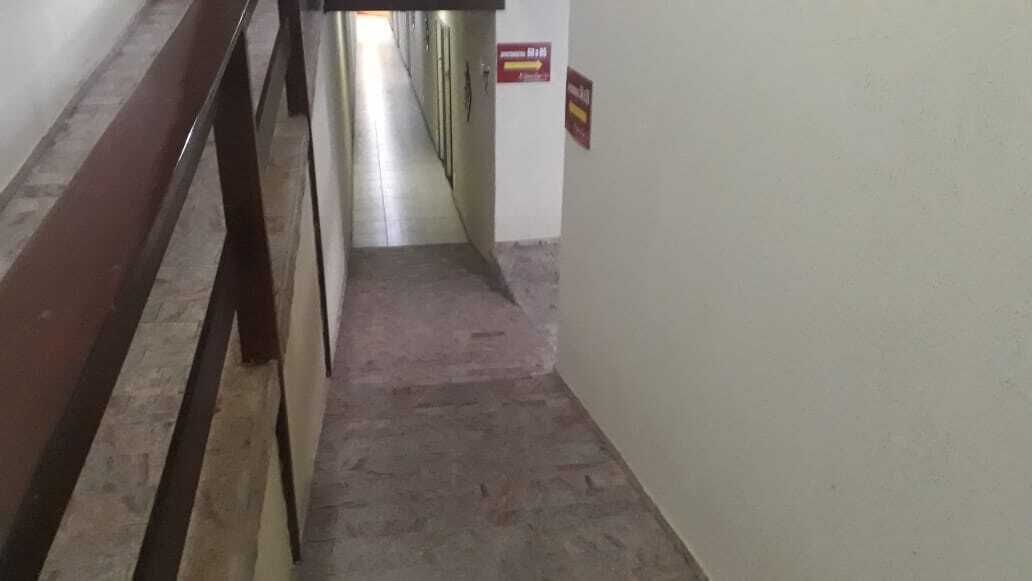 Un pasillo estrecho con una barandilla metálica a la izquierda y un cartel en la pared derecha.
