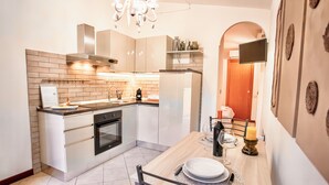 A modern kitchen with a built-in oven, a dining table with chairs, and a TV mounted on the wall. - Two-room apartment with private garden 4 km from Marmore Falls. (Terni)