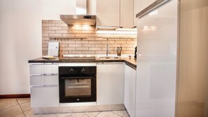 A modern kitchen with white cabinetry, a black oven, and a stainless steel range hood. - Two-room apartment with private garden 4 km from Marmore Falls. (Terni)